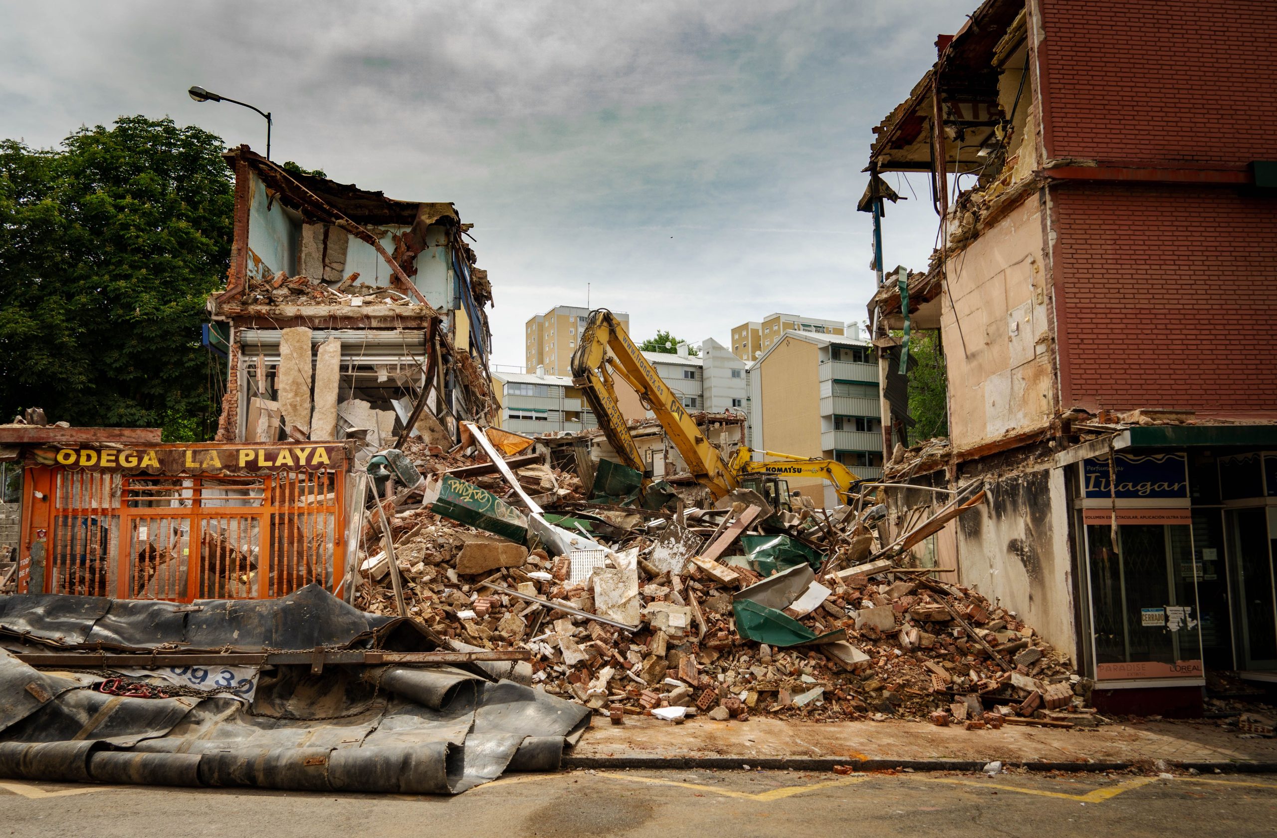 service-1 Dramatic demolition of urban building with rubble and excavator at work.